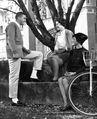 University of Idaho students Carl Grover Berry, Nancy Jane Trail, and Camille Carolyn Shelton sit on the 'I' Bench in front of the administration building.