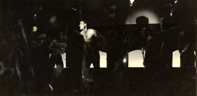 Scene during the University of Idaho drama production of "Hairy Ape." A man can be seen standing on stage, while other men stand around watching. Directed by Fred Blanchard, set by Theodore Prichard