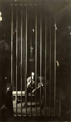 Scene during the University of Idaho drama production of "Hairy Ape." A man can be seen sitting behind bars on stage. Directed by Fred Blanchard, set by Theodore Prichard.