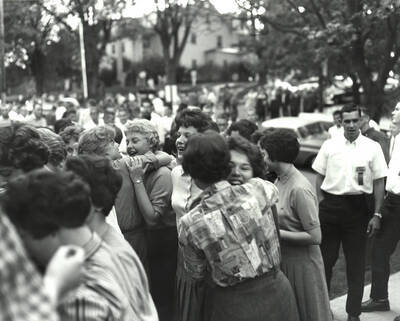 Male students look on as returning members of Delta Gamma embrace the new members of the sorority.