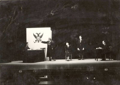 Scene from the University of Idaho drama production of "The Living Corpse." Directed by Fred Blanchard, Technical Director Theodore Prichard. In this scene, Fedya stands before the magistrate and says 'I'm dead, dead, and far beyond your power.' Cast members include Fred C. Blanchard as Fedya, Ethlyn O'Neal as Lisa, Clayne Robison as Victor, Alberta Bergh Utt as Masha, Raphael Gibbs as Prince Sergius, Erma Lewis as Anna Pavlovna, Casady Taylor as Petrovitch, Earl Bopp as Artimiev, and Joe Paquet as Petushkov.