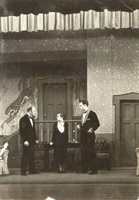 Scene from the University of Idaho drama production of "Hawk Island." Directed by Fred Blanchard, Technical Director Theodore Prichard in the University Auditorium. In this scene, Lloyd Ruitel, Margaret Moulton and Leland Cannon are talking on stage. Members of the cast include Lloyd Ruitel as Paul Cooper, Robert Herrick as Anthony Bryce, Margaret Moulton as Sally Rogers and Alberta Bergh Utt as Madeline Austin.