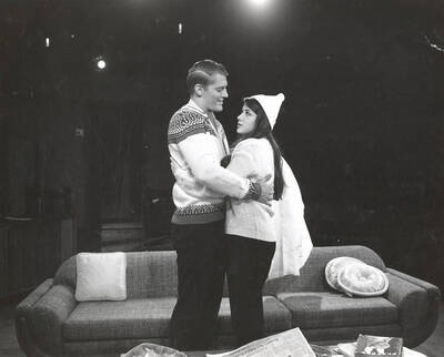 Scene during the University of Idaho drama production of "Come Blow Your Horn." Directed by Edmund Chavez for Summer Theatre in the Field House. A man and a woman can be seen hugging each other on set.