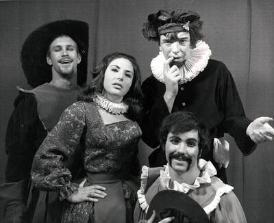 Publicity photo of Summer Theatre and tour group for the University of Idaho drama production of "Taming of the Shrew." This production was directed by Edmund Chavez. Four cast members can be seen dressed in costume and posing for a picture. The Summer Theatre shows were staged in the Field House.