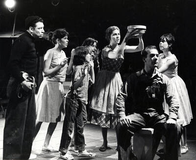 Scene from the University of Idaho drama production of "The Great Big Doorstep."  ASUI production directed by Jean Collette in the University Auditorium. A woman can be seen holding a bowl above her head as the other actors look on.