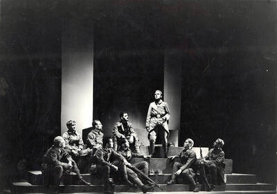 Scene from the University of Idaho drama production of "Paths of Glory." ASUI production was directed by Jean Collette, costumes by Marion Featherstone. A man can be seen standing on stage, while other actors look on.