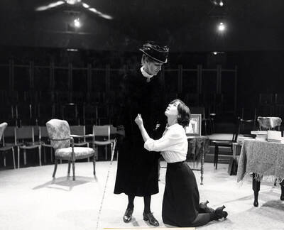 Scene from the Summer Theatre production of "Anastasia." Directed by Robert Thompson in the Kiva. One woman can be seen kneeling and holding onto another woman. PG 2_141-170 shows a rehearsal photo of the same moment.