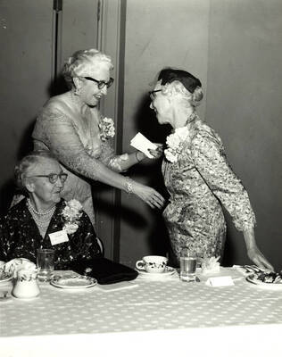 Two alumnae stand to give recognition and speeches during the 50th anniversary dinner of Gamma Phi Beta.