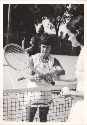 An unnamed women's Tennis instructor demonstrates the correct grip to a player.