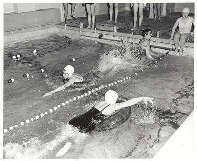 Idaho women's swimmers using inner-tubes during an event in Memorial Gymnasium basement.