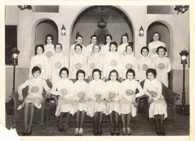 A group photo of the Spurs, a national honorary service organization, in an unidentified building's living room.