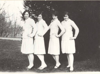 Four members of the Spurs, a national honorary service organization, stand outside the Administration Building near the tennis courts. Individuals identified from left to right: Louise Braham, Leona Deidrickson, Marjorie Drager, Marian White.
