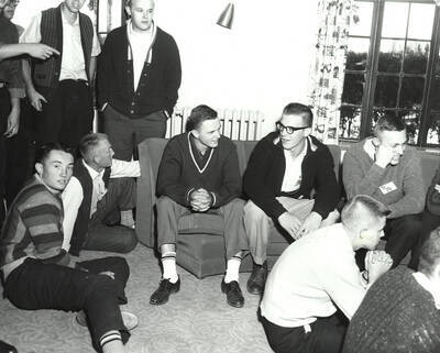 Current and potential Delta Tau Delta members sit in the house living area talking to one another during rush week.