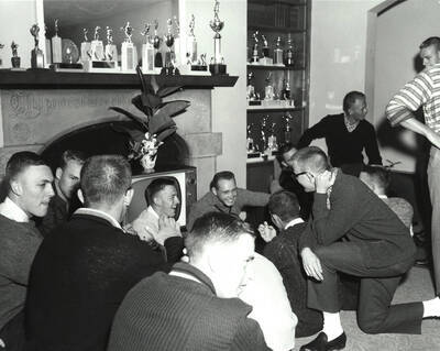 A group of men sit in the Delta Tau Delta living area relaxing and talking during rush week.