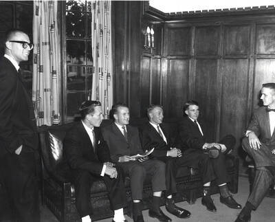 Men in sports coats sit and talk with current Beta Theta Pi members during rush week.