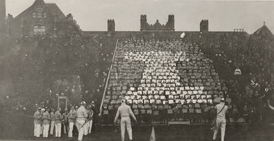 Yell Kings and Dukes lead a coordinated cheer in front of the card section of the audience during a football game.