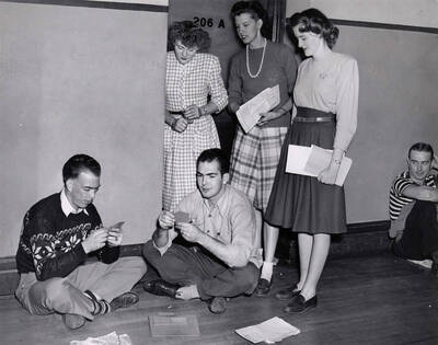 Two students play cards while waiting in line for registration in the Administration Building.