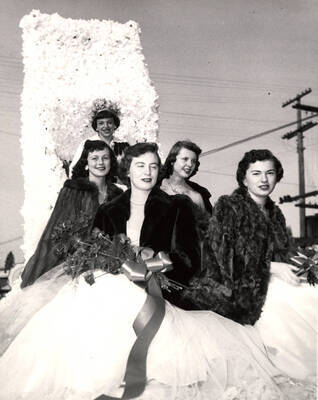 Homecoming royalty ride on a float during the Homecoming parade. Jan Cole (Queen), Lorna Hobdey, Nancy Westerberg, Nancy Lyle, Susie Oberg ride on the queen's float.
