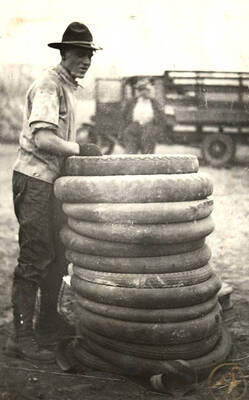 An unidentified man in a rangers uniform stacks tires as part of preparations for the Homecoming Freshman bonfire.