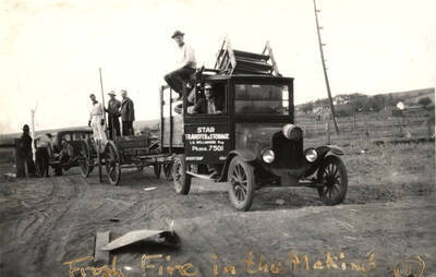 Men stand on trailers while loading supplies for the Homecoming Freshman bonfire. The caption on the photograph reads: 'Frosh Fire in the Making'.