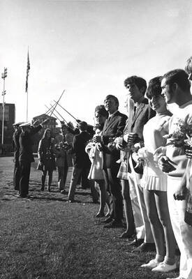 Glennis Conner, Homecoming queen, and her escort walk through an arch of swords as part of the Homecoming royalty ceremony.
