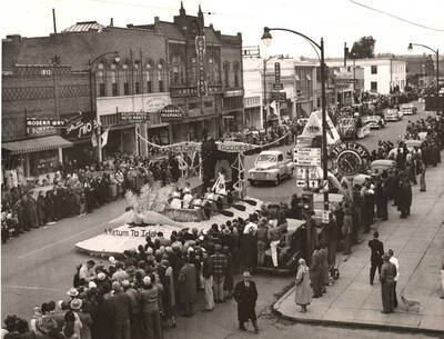 A wide-angle view of the Homecoming Parade going down main street with spectators lining the sidewalks.