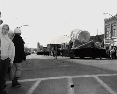 An unidentified float in the Homecoming parade. Three children can be seen among the spectators in the foreground.