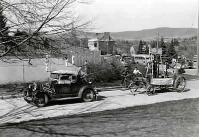 An old Ford pulls a wooden wagon showcasing an anti-lawyer wagon, featuring signs that read, 'Lawyers take heed' and 'Too Much Bull' during Idaho's Little International Agriculture Show.