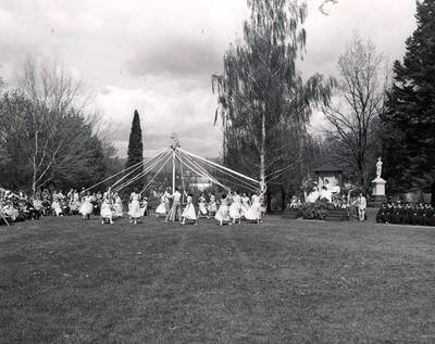 A far-shot of students winding the maypole during Idaho's Mother's Day celebrations, the Spanish-American War memorial is seen in the background.