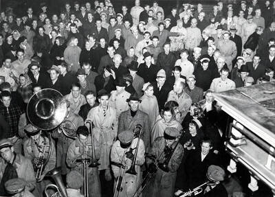 The Idaho pep band plays in a circle for a large crowd of people prior to a football game.