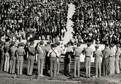 A shot from behind of the Idaho pep band playing in front of a sitting student section during a football game.