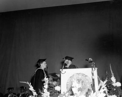 Idaho President Donald R. Theophilus shakes hands with Women's Dean Louise Carter and hands her the Citation of Merit.