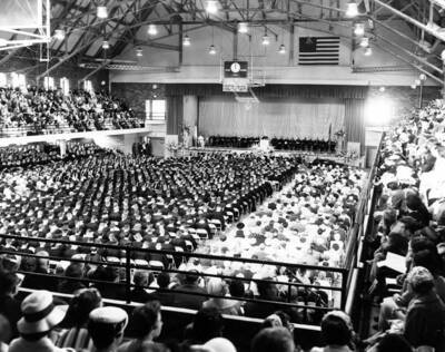 An audience watches from the balconies of Memorial Gymnasium while University of Idaho students await the beginning of commencement addresses.
