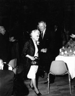 Idaho Governor Donald Samuelson walks with Margaret McCallie Moore of the class of 1898.