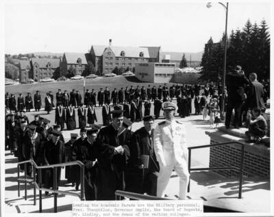 Military personnel, University of Idaho President Donald R. Theophilus, Governor Smylie, the Board of Regents, Mr. Lindley, and Deans of various Colleges lead the academic parade into Memorial Gymnasium for commencement.