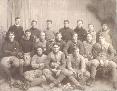 Kays holds a ball with writing, '12-11-99,' as the team poses in front of a curtain indoors. Players pictured: Back) ?, Martin, McConnel, Horton, Gibson, Gilbreth, ?; Center) Tweedt, Smith, Jenkins, Bundy, Gibb, Rains, Barton; Front) Mix, Kays, Burr.