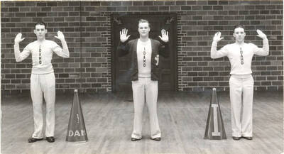 Football cheerleaders, including yell king Johnny Thomas, Vernon Eaton and 'Dukes,' Harry Wilson pose in cheer stances inside Memorial Gymnasium.