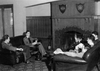 Students sitting around the living room in the Phi Delta Theta house, which is on the southeast corner of Elm Street and Idaho Avenue.