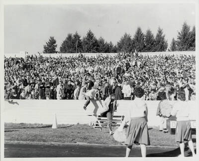 Fans stand in the bleachers in front of Idaho's cheer team. Several spectators can be seen hopping the barricade and running toward the field.