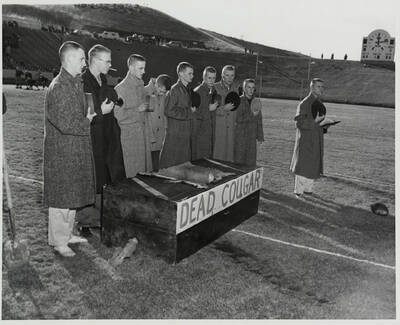 Idaho fans sarcastically salute a coffin with cougar skin on top of it, with the words reading 'Dead Cougar' on the front.
