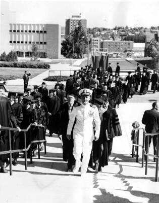 Deans, faculty, and graduates walk into Memorial Gymnasium as part of the Graduate Walk prior to Commencement.