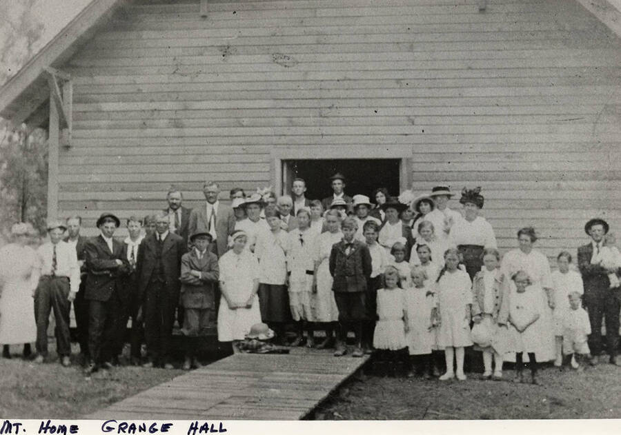 A group of at least 45 people at the Mountain Home Grange Hall. The Mountain Home Grange was organized in 1931 and the hall dedicated in 1936. A front entry building was later added around 1939.