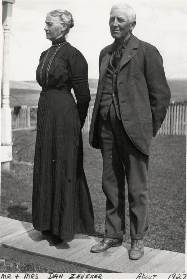 Mr. and Mrs. Dan Zedeker standing together for a photograph in front og ther house and fields.  Photograph taken aroun 1927.