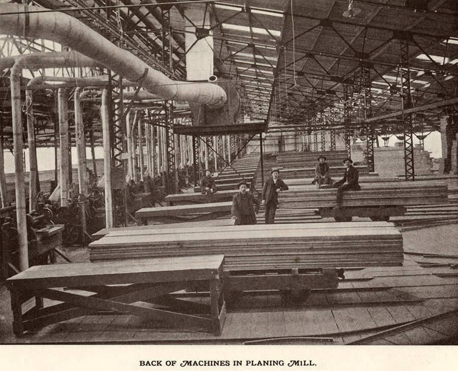 Employees posing at the back of the machines used in the planing mill.