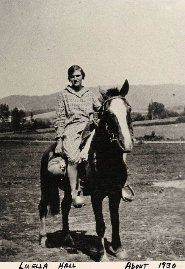 Luella Hall riding a horse in a field.  Photograph taken about 1930.