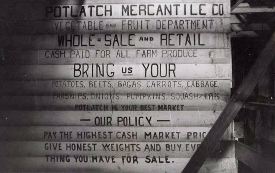 A photograph of a sign for the Potlatch Mercantile Company stating they are whole sale and retail. It states they pay highest cash market price for honest weight of everything you have for sale.