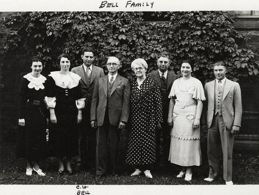 C. W. Bell and the Bell Family pose for a photograph in front of an ivy covered building.