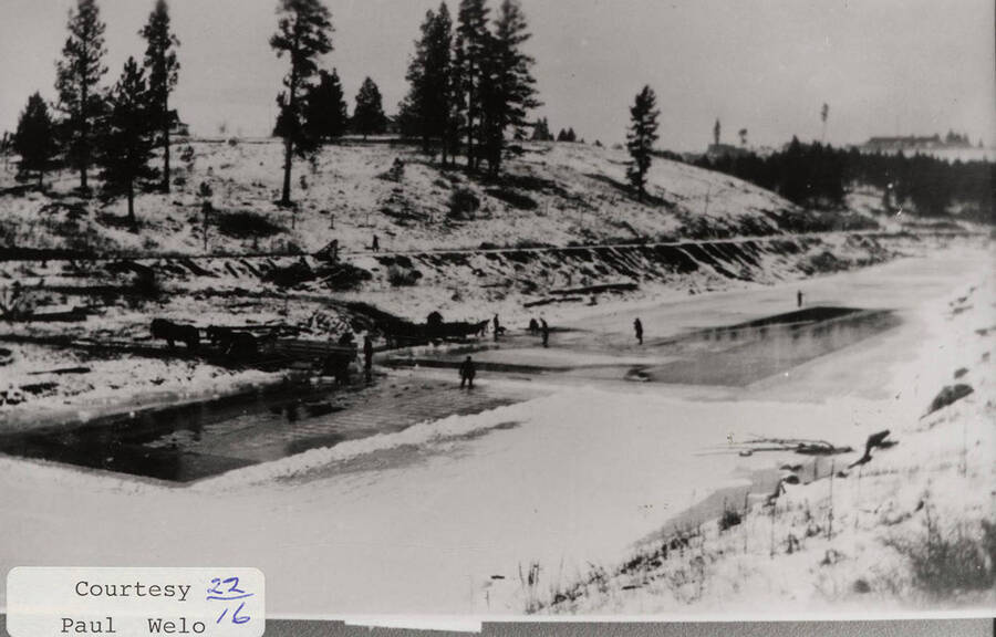 A photograph of the icy pools where men have been ice cutting.