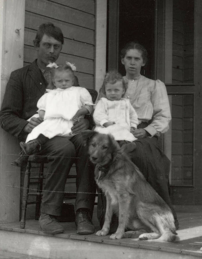 A photograph of an unknown family group with their dog.