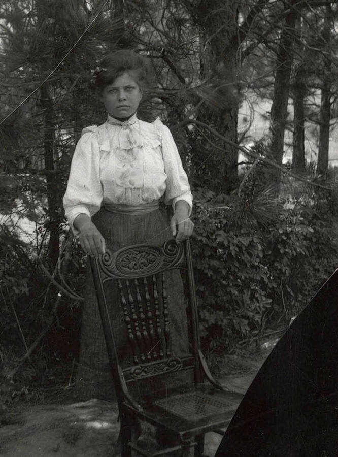 A photograph of an unknown woman with a chair.
